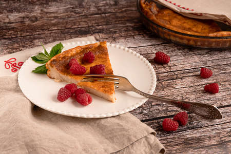 Sweet home-made cheesecake served with raspberries on a white plate on vintage wooden backgroundの写真素材