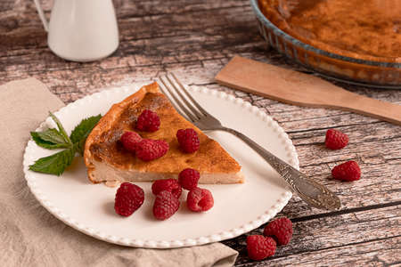 Sweet home-made cheesecake served with raspberries on a white plate on  woodenの写真素材