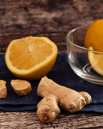 Pieces of organic ginger root and slices of lemon dark, as ingredients for hot ginger tea, on dark wooden backgroundの写真素材