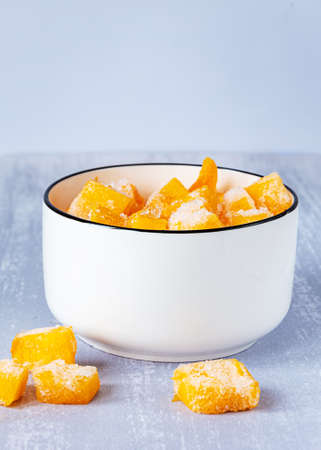 Frozen pieces of pumpkin in a white bowl on gray tableの写真素材