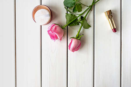 Top view arrangement with make-up, roses and copy-space on white wooden background. Women's day, beauty and femininity concept.の写真素材