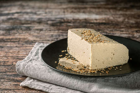Tahini halva on wooden background, with sesame seeds as its main ingredient, copy space