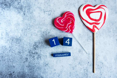 Top view of 14 February lettering and two heart-shaped lollypops on grey concrete background, copy spaceの写真素材