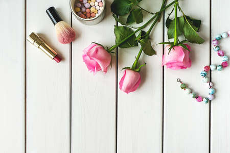 Top view arrangement with make-up, roses, necklace and copy-space on white wooden backgroundの写真素材