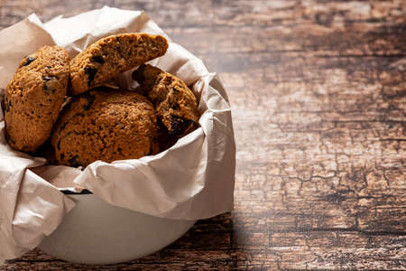 A bowl with homemade chocolate cookies on the vintage wooden background, with copy spaceの写真素材