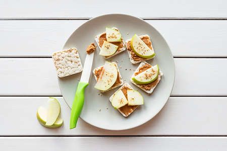 Healthy breakfast with peanut butter and apple sandwiches on rice cakesの写真素材