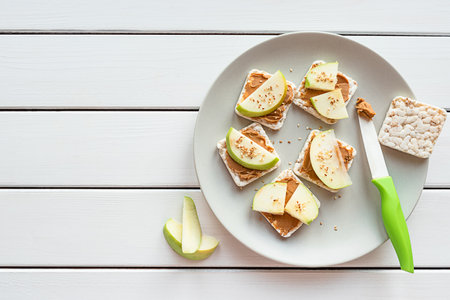 Healthy breakfast with peanut butter and apple sandwiches on rice cakesの写真素材