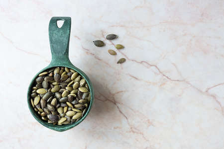 Pumpkin seeds in a scoop on marble backgroundの写真素材