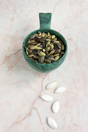 Pumpkin seeds in a scoop on marble backgroundの写真素材