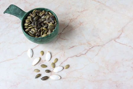 Pumpkin seeds in a scoop on marble backgroundの写真素材