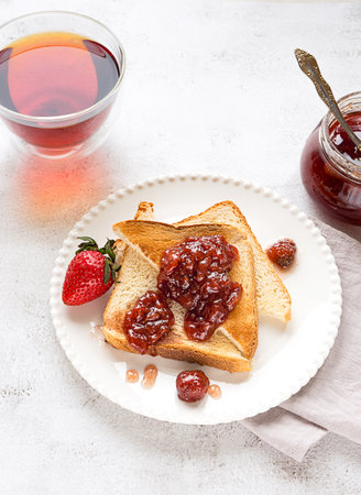 Toasted bread slices with strawberry jam and cup of teaの写真素材