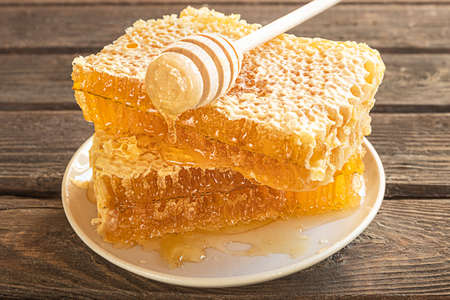 Pieces of honeycomb on a plate and a honey spoon