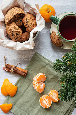 A peeled tangerine, chocolate cookies and a fir tree branch