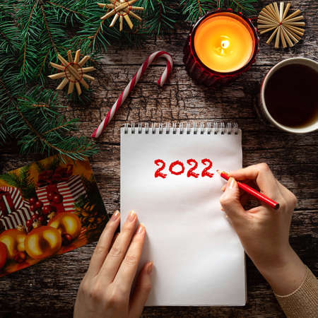 Womans hand writing on a notepad sheet in Christmas settingの写真素材