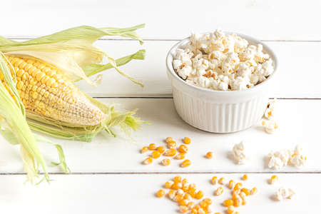 Popcorn, corn cob and corn grains, top view on a white wooden backgroundの写真素材