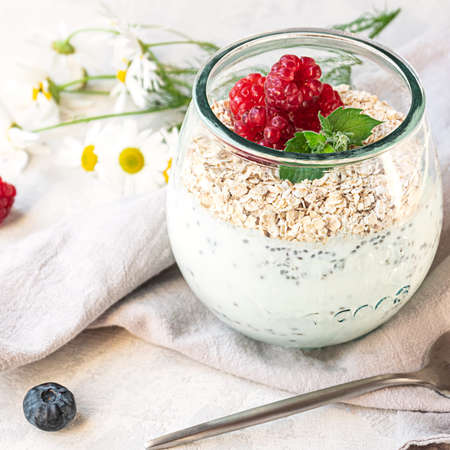 A glass with layered yogurt, chia seeds, oats and berries, gray concrete tabletop. Healthy breakfast, healthy lifestyle conceptの写真素材