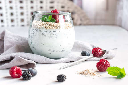 A glass with layered yogurt, chia seeds, oats and berries, gray concrete tabletop. Healthy breakfast, healthy lifestyle conceptの写真素材
