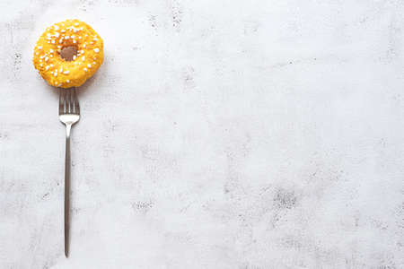 Donut on a fork, flat lay on gray concrete background. Concept of a dessert and high calories diet. Copy space.の写真素材