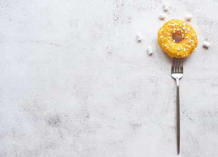 Donut on a fork, marshmallows, flat lay on gray concrete background. Concept of a dessert and high calories diet. Copy space.の写真素材