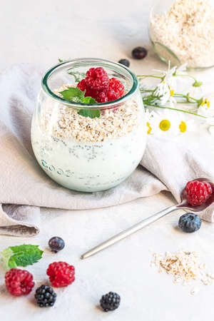 A glass with layered yogurt, chia seeds, oats and berries, served for breakfastの写真素材