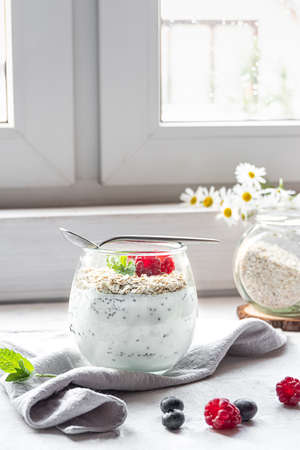 A glass with layered yogurt, chia seeds, oats and berries, served for breakfastの写真素材