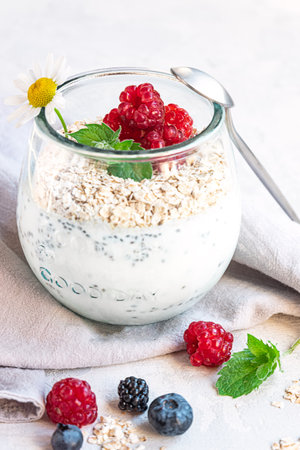 A glass with layered yogurt, chia seeds, oats and berries, served for breakfastの写真素材