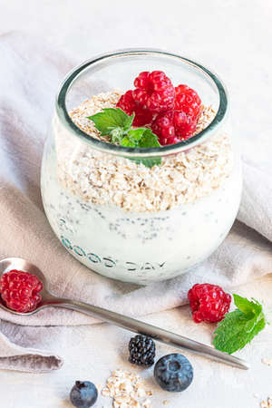 A glass with layered yogurt, chia seeds, oats and berries, served for breakfastの写真素材