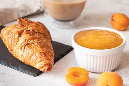 Fresh croissant with apricot jam and coffee. French breakfast conceptの写真素材