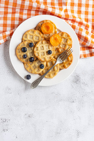 Small round waffles and fruits on grey background, flat layの写真素材