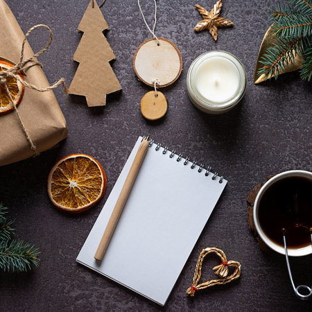 Eco-friendly and crafted Christmas decorations, fir branches, tea and a notebook on dark backgroundの写真素材