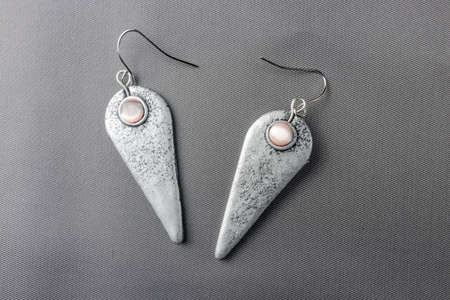 Hand made custom earrings polymer clay on grey fabric background lit from aboveの写真素材