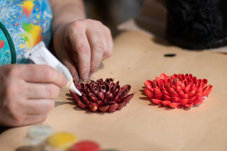 Female artist is making a design of decorative flowers with painted nut shellsの写真素材