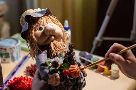 Female artist is using a painting brush on fairytale character Domovoy that looks like an old man from medievalの写真素材