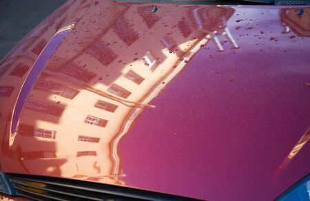 Reflection of buildings in a cowl of the car after a rainの写真素材