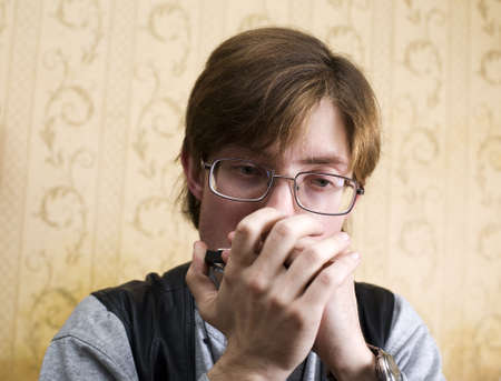 young man in glasses playing the harmonicaの写真素材