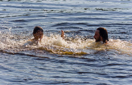 man and woman splashing in the summer lakeの写真素材