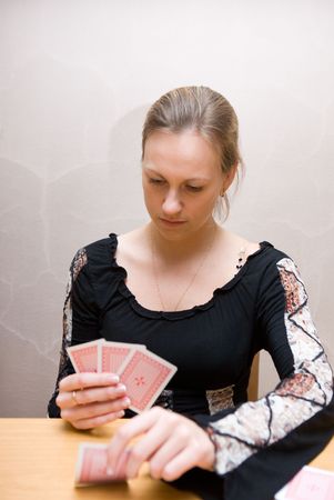 young beautiful girl sitting at the table reading cardsのeditorial素材