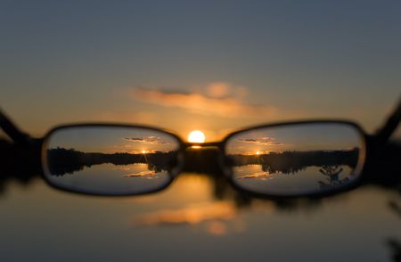 view on a sunset on lake through glassesの写真素材