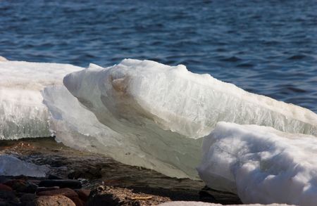 Melting ice fragments on granite river bank, water on backgroundの写真素材