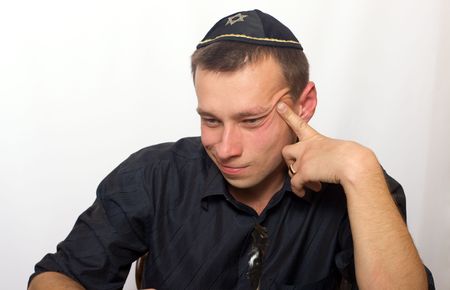 Portrait of the thoughtful young man dressed in a black shirt and skullcapの写真素材