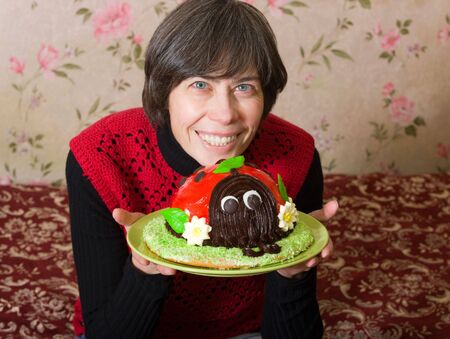 Happy woman with a cake in her handsの写真素材