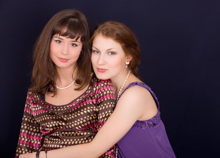 Portrait of two beautiful girl-friends on black backgroundの写真素材