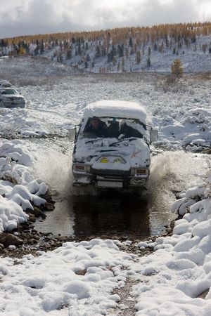 The car moves ford in mountain small river in the winter