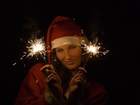 The girl in a suit of Santa Claus with Bengal firesの写真素材