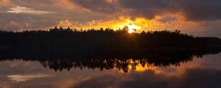 Bright decline with clouds over wood lakeの写真素材