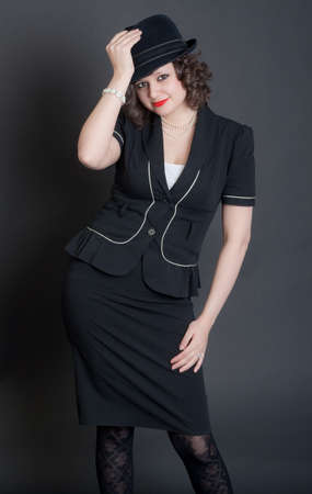 the elegant girl in a black suit and a hat