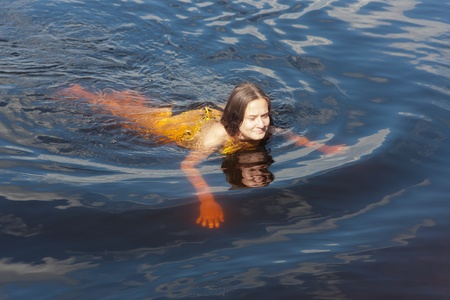 the girl swims in blue summer water の写真素材