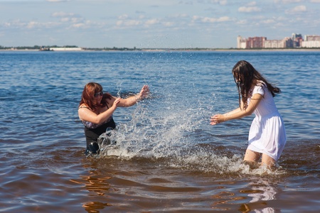 two girlfriends have fun on a beach in waterの写真素材