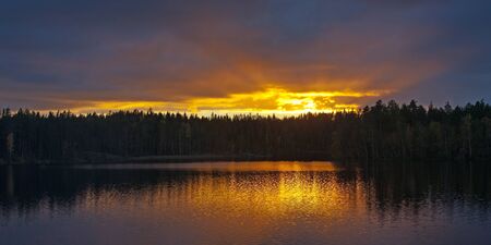 he last beams of the evening sun over the wood lakeの写真素材