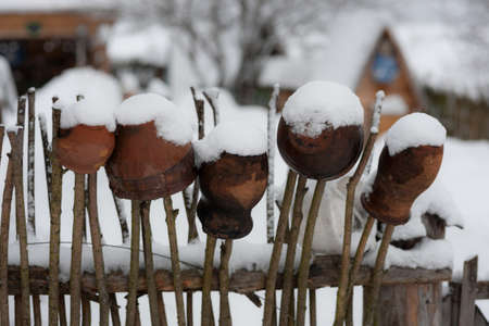 rustic fence with clay pots on a winter dayの写真素材